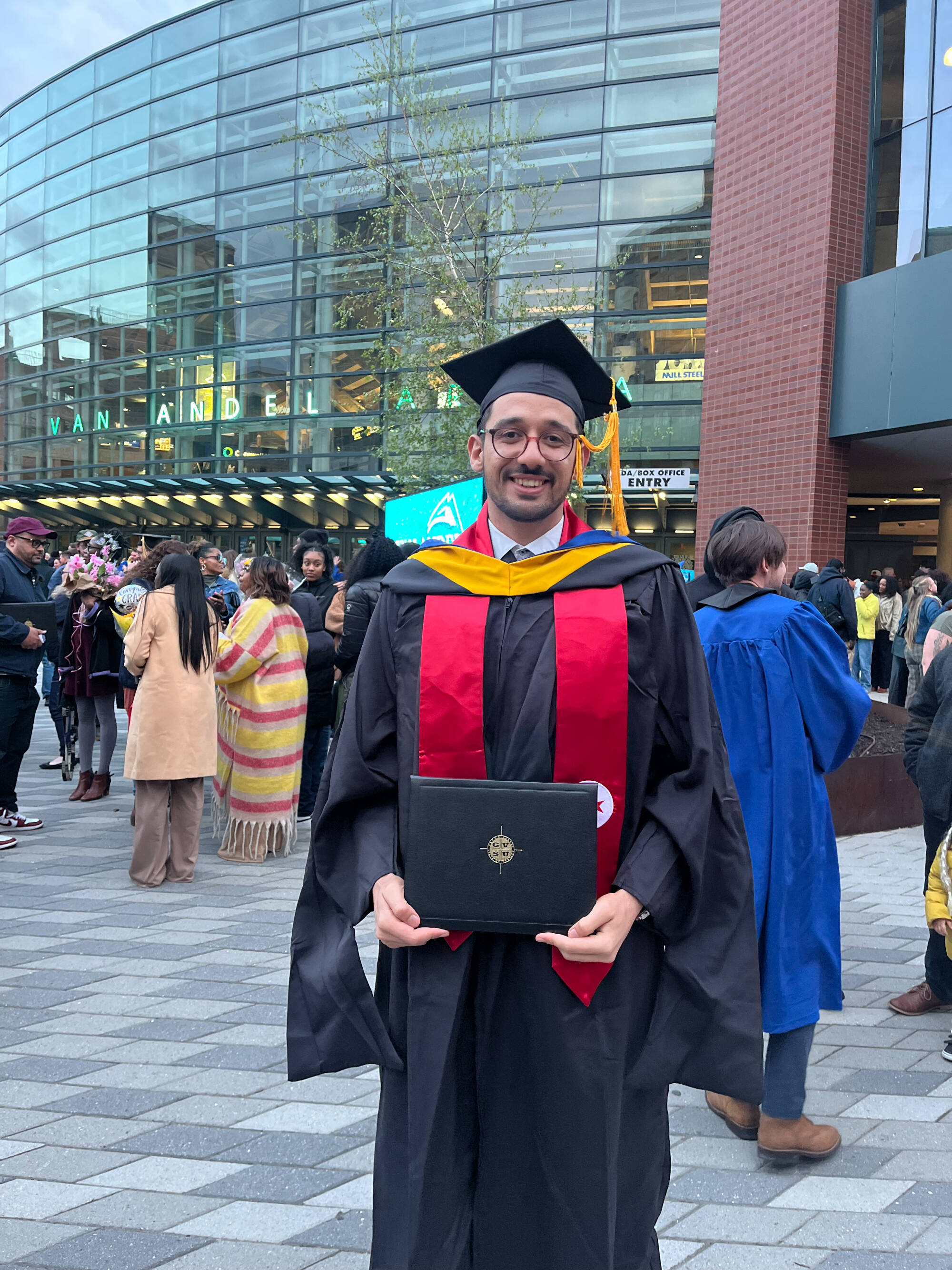 graduated student standing downtown in front of VanAndel arena